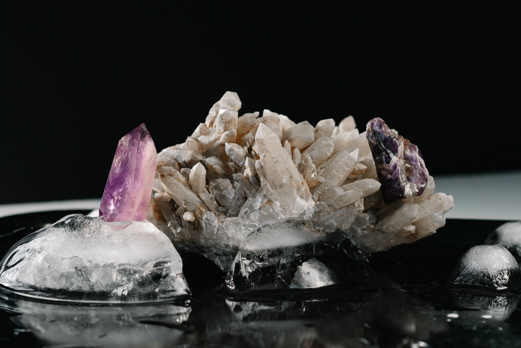 Amethyst and clear quartz crystals on a dark surface for a beginner guide to crystal meanings and benefits
