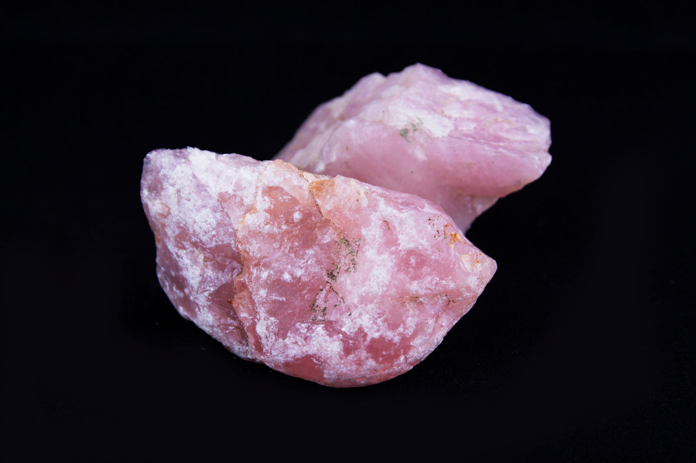 Natural raw rose quartz crystals on a black background for a guide to rose quartz meaning