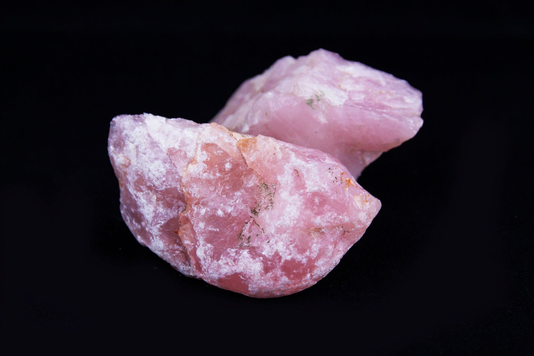 Natural raw rose quartz crystals on a black background for a guide to rose quartz meaning