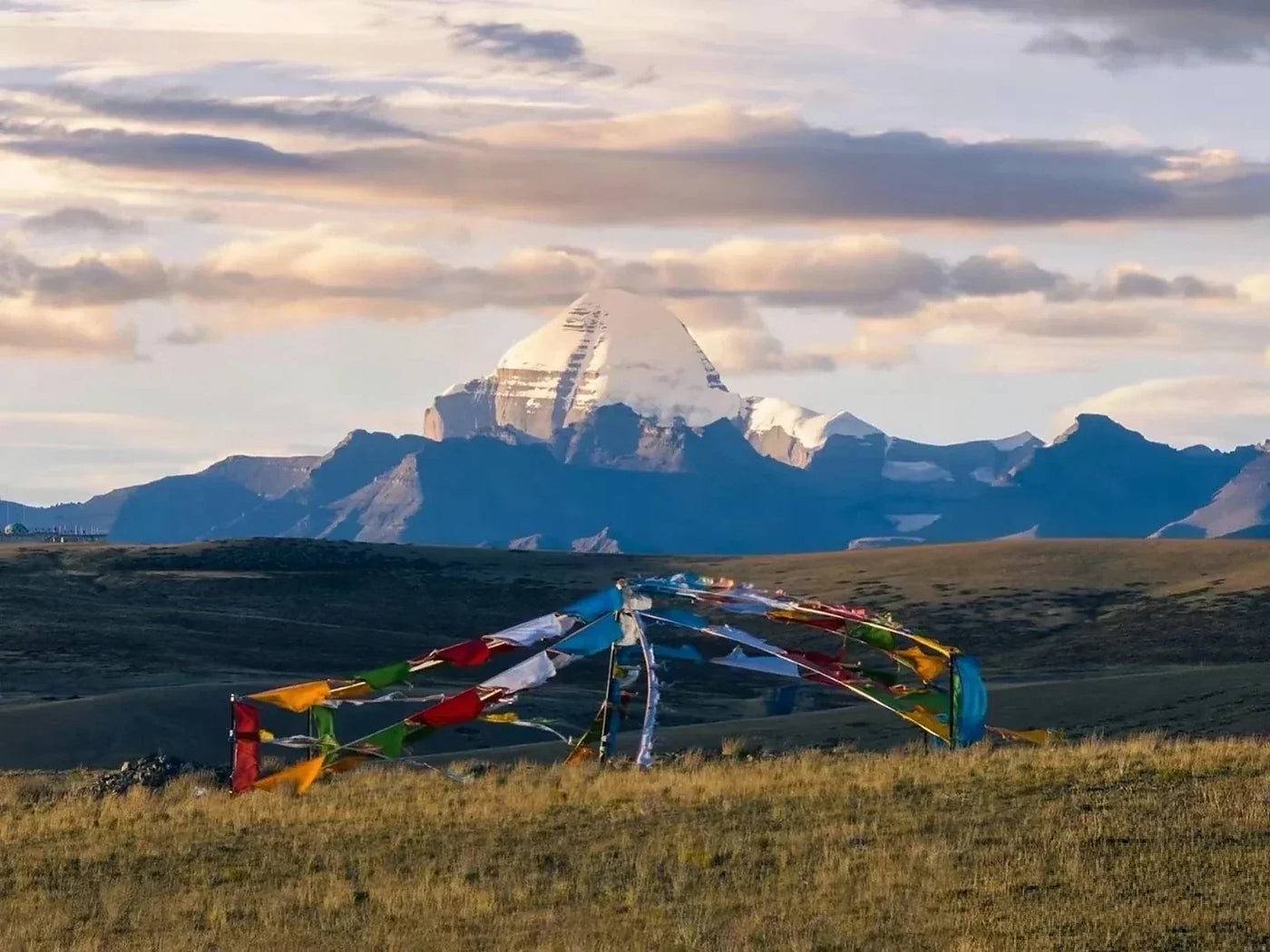 Tibetan prayer flags in a Himalayan landscape with a snow-covered sacred mountain in the distance