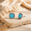 Kailora Tibetan turquoise stud earrings shown at a 45 degree angle on warm stone thumbnail 5 | Kailora