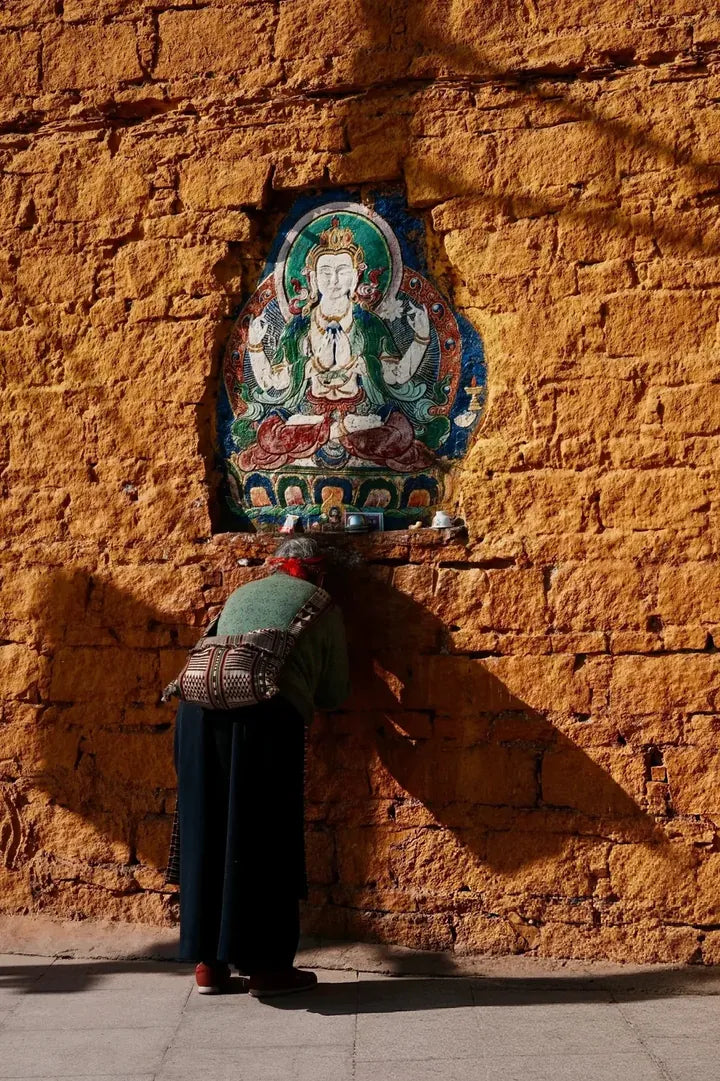 Contemplation before traditional Tibetan wall imagery