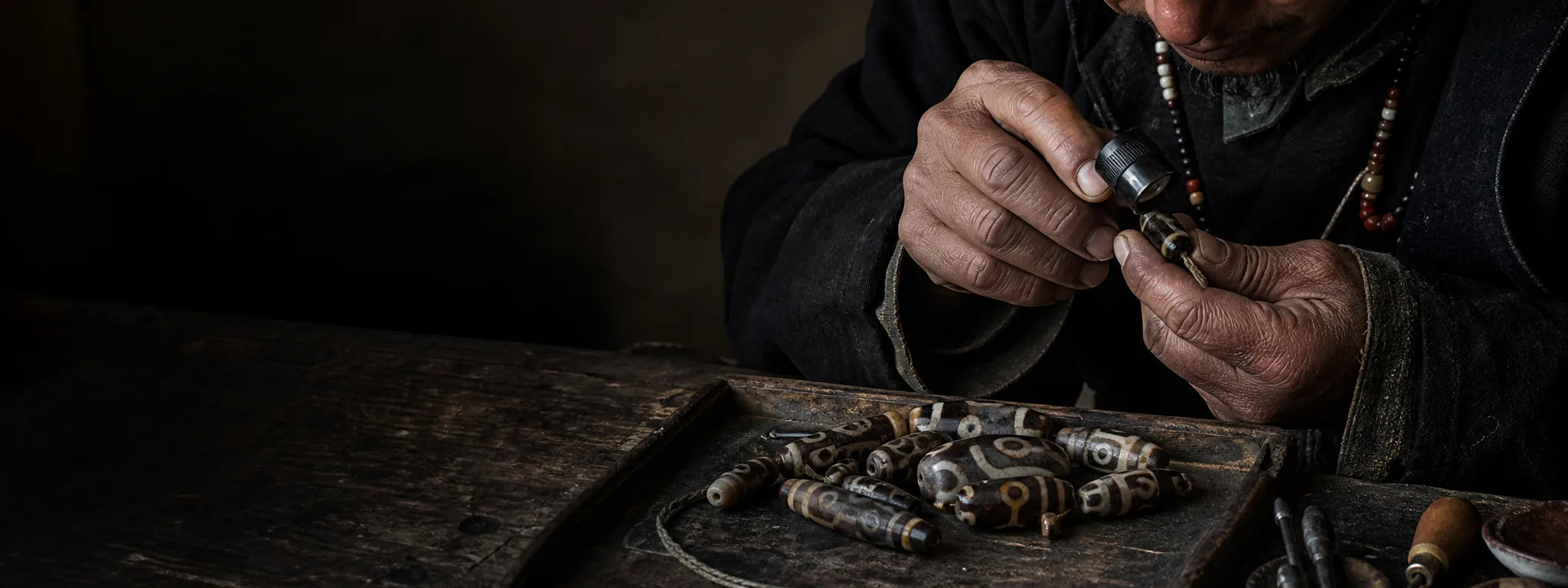 Tibetan-inspired artisan scene examining naturally textured Dzi-style agate beads
